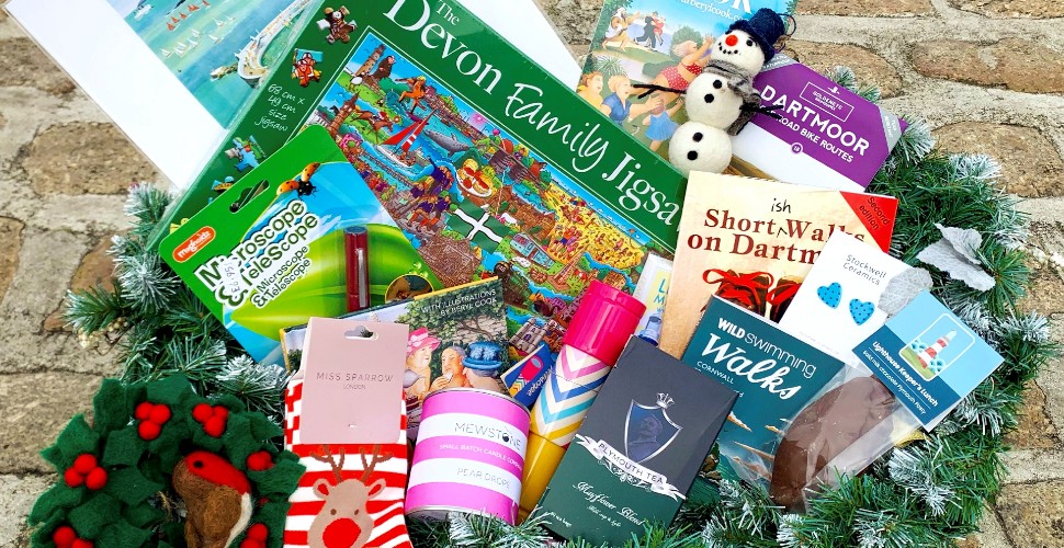 A collection of presents from the Tourist Information Centre inside a hamper, including a jigsaw, fluffy socks, decorations and books.